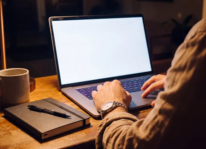 The owner at a desk at half past nine at night rating a conversation in the training log, the old paper notebook closed beside the laptop.